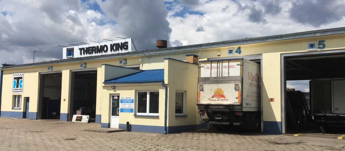 Serwis Apex Thermo King Bydgoszcz - na zdjęciu widać budynek główny, 4 otwarte bramy wjazdowe dla ciężarówek, w jednej jest ustawiony samochód, przygotowany do diagnostyki.